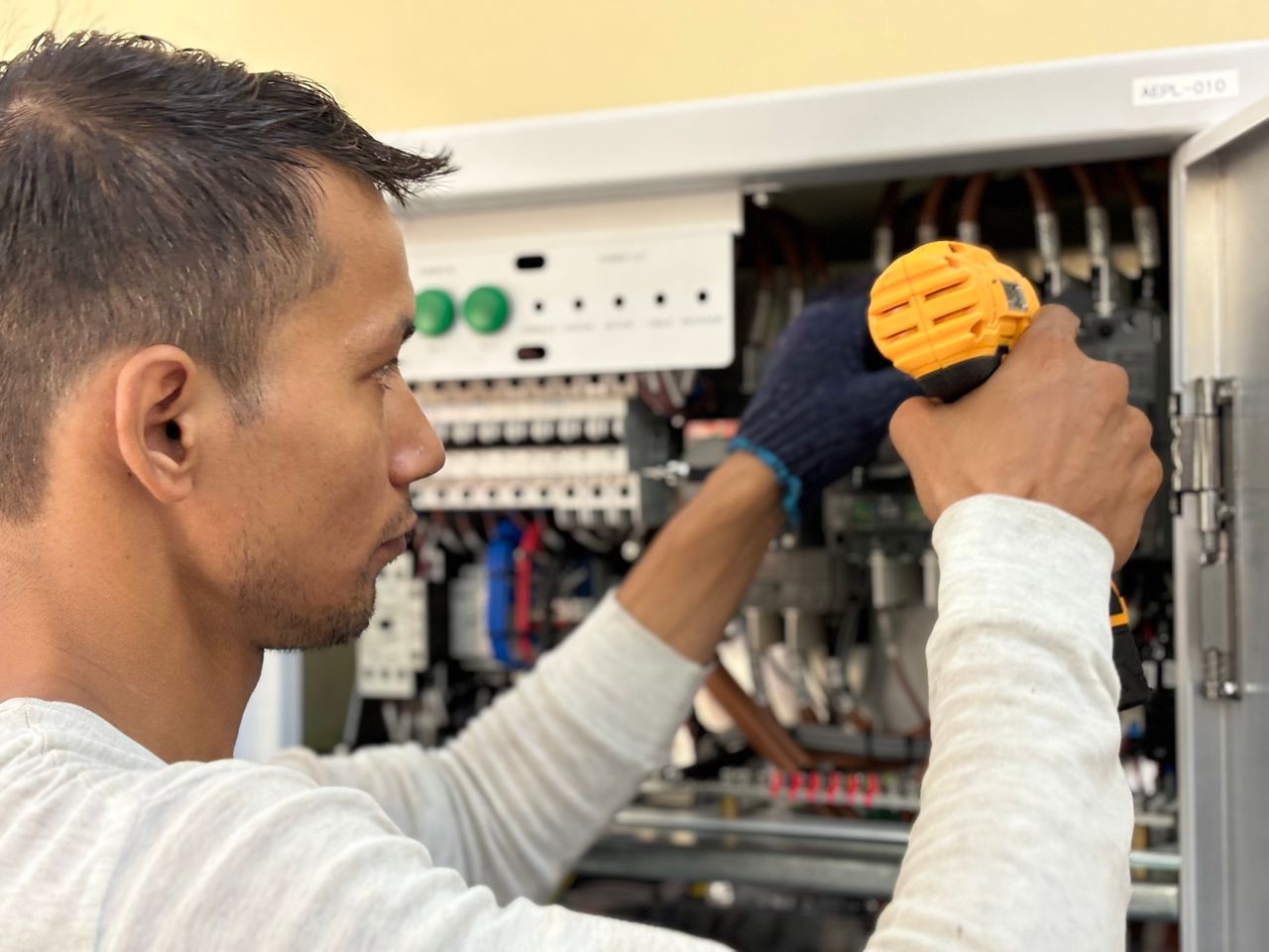 Home Focused technician using a drill on an electrical panel, showcasing expert workmanship.