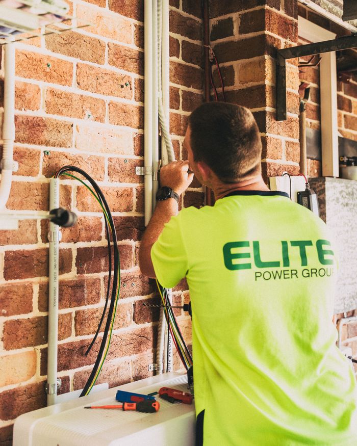 Electrician working on solar energy wiring installation, ensuring efficient electrical system indoors.